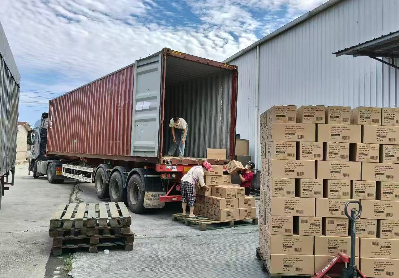 Garment cartons being loaded into a shipping container outside an apparel factory