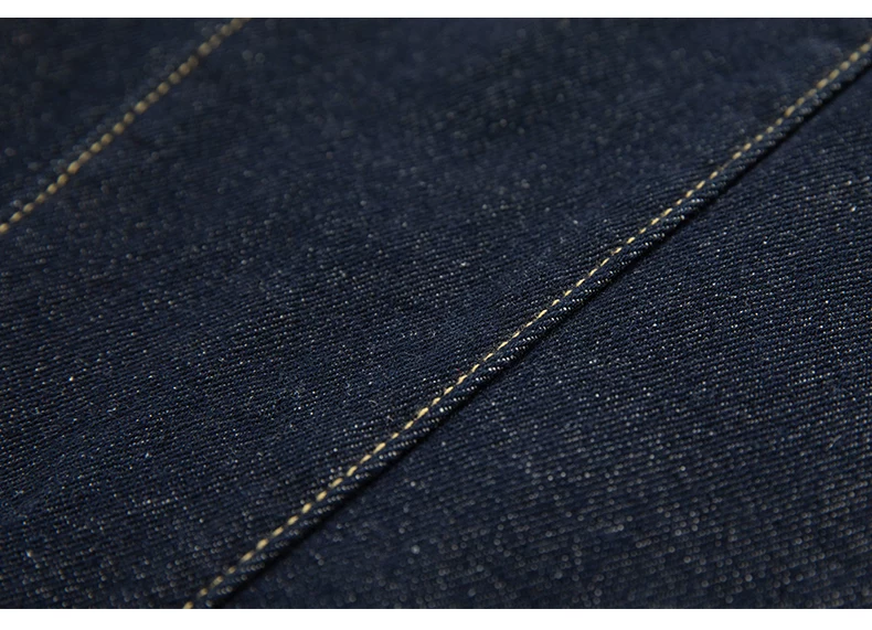 Denim fabric surface and stitching detail on dark navy jeans