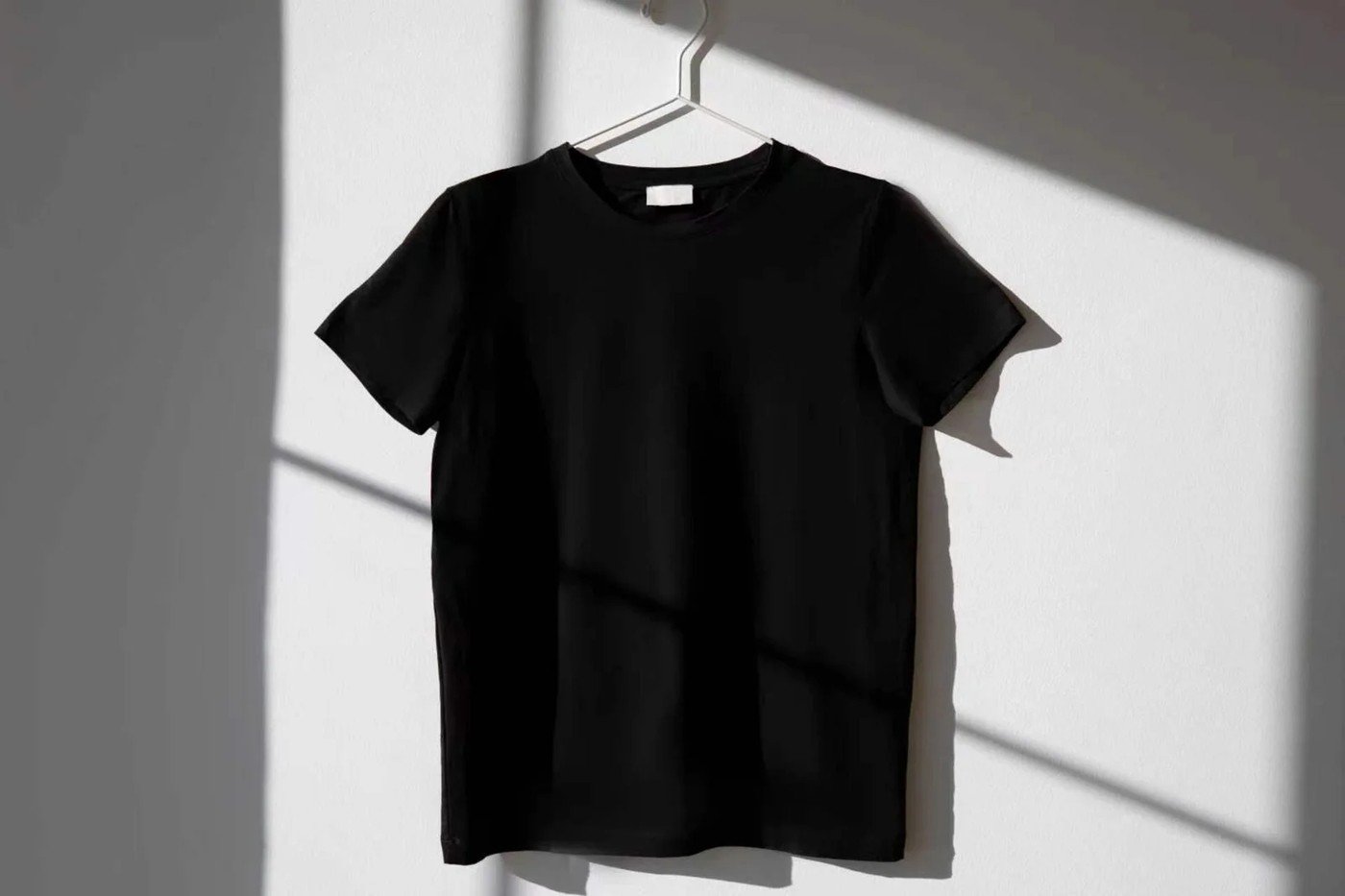 Black crew-neck T-shirt on a hanger with a blank neck label, ready for custom branding