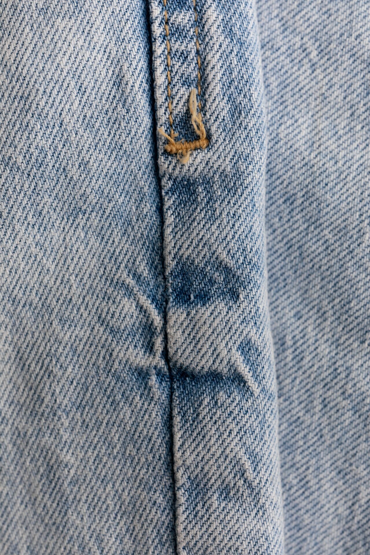 Light wash denim seam with contrast topstitching and frayed threads detail