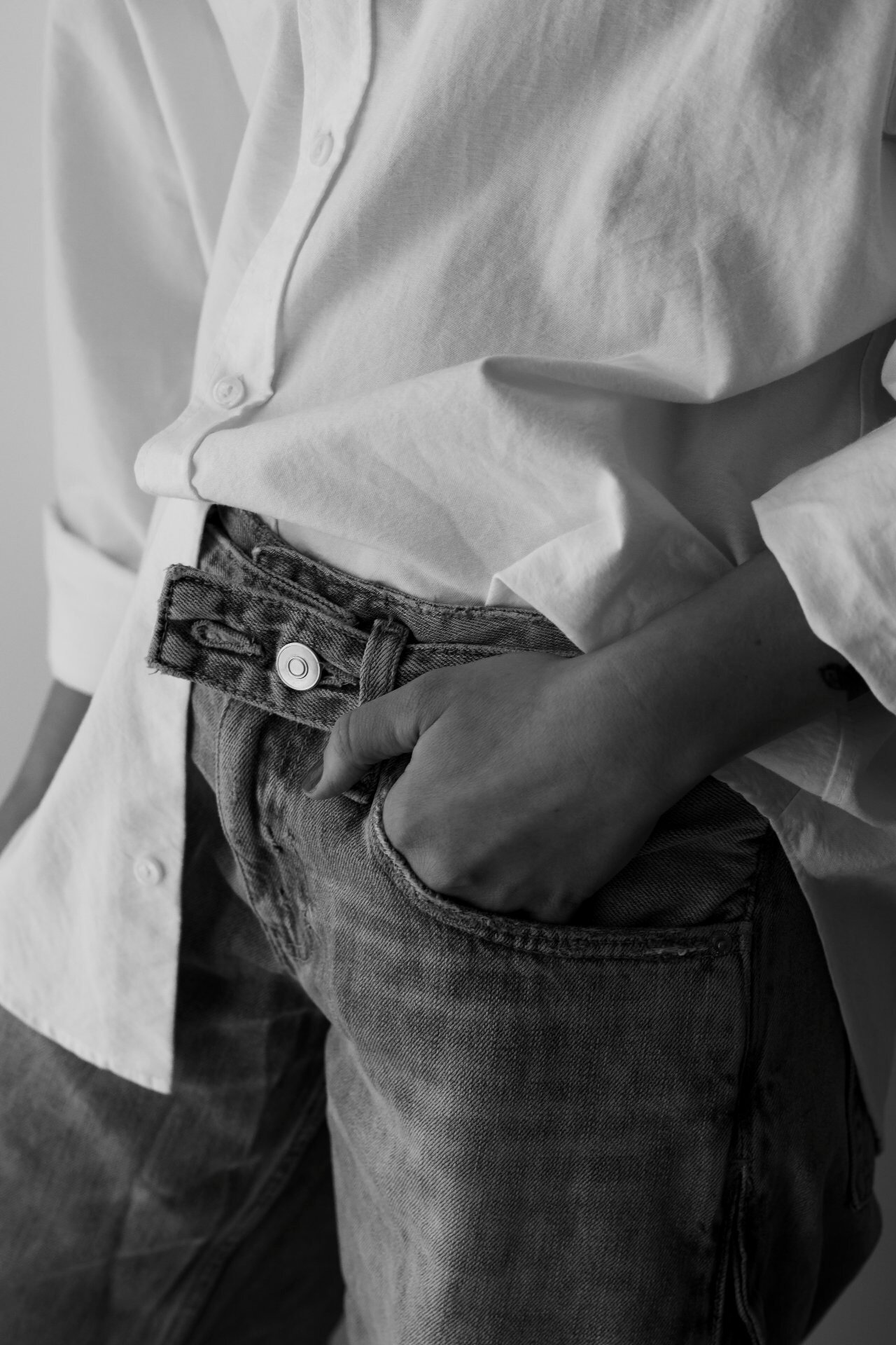 Black and white photo of hand in denim pocket with white shirt styling detail