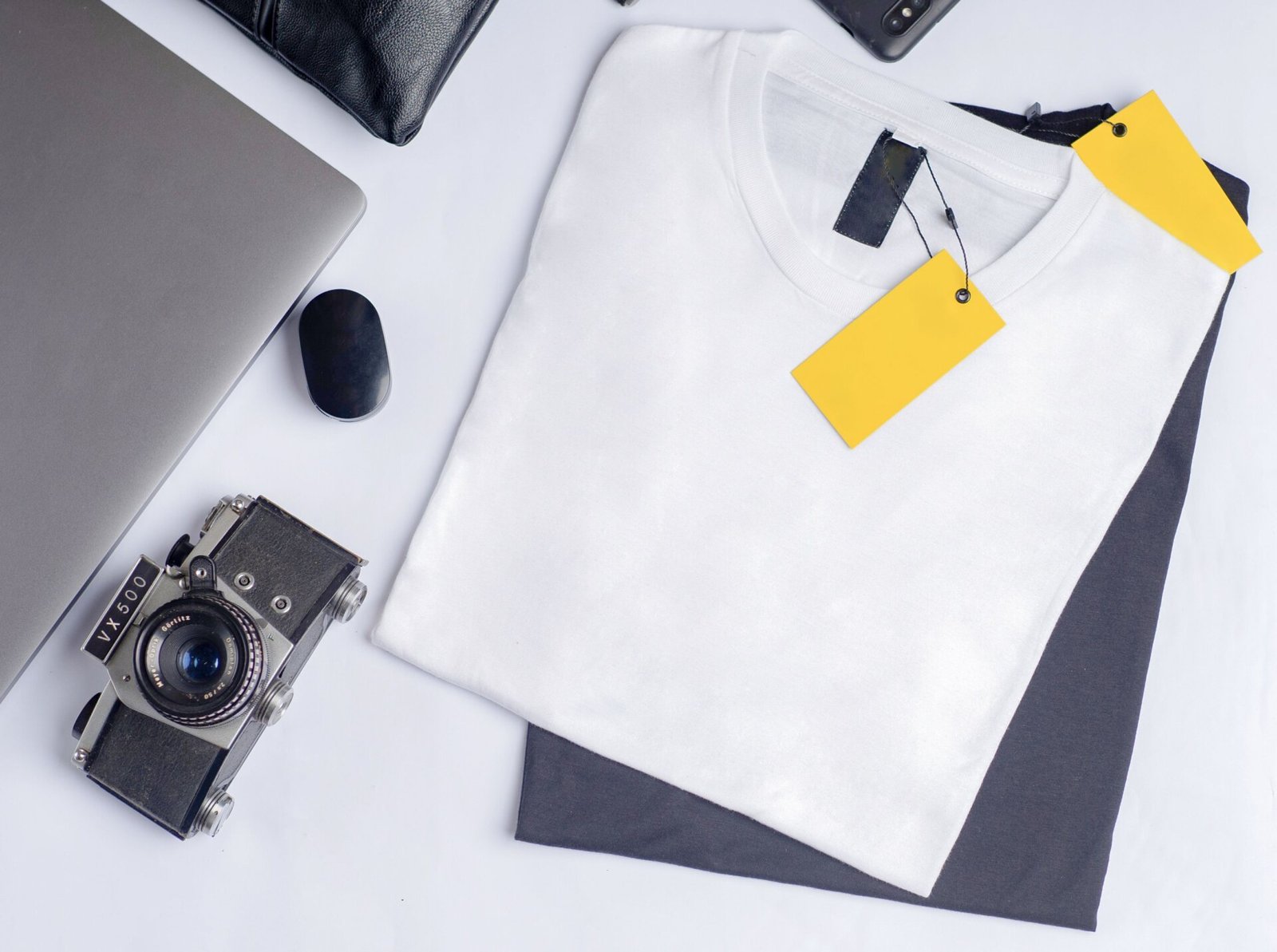 White crew-neck t-shirt flat lay with blank private label hang tags, ready for branding