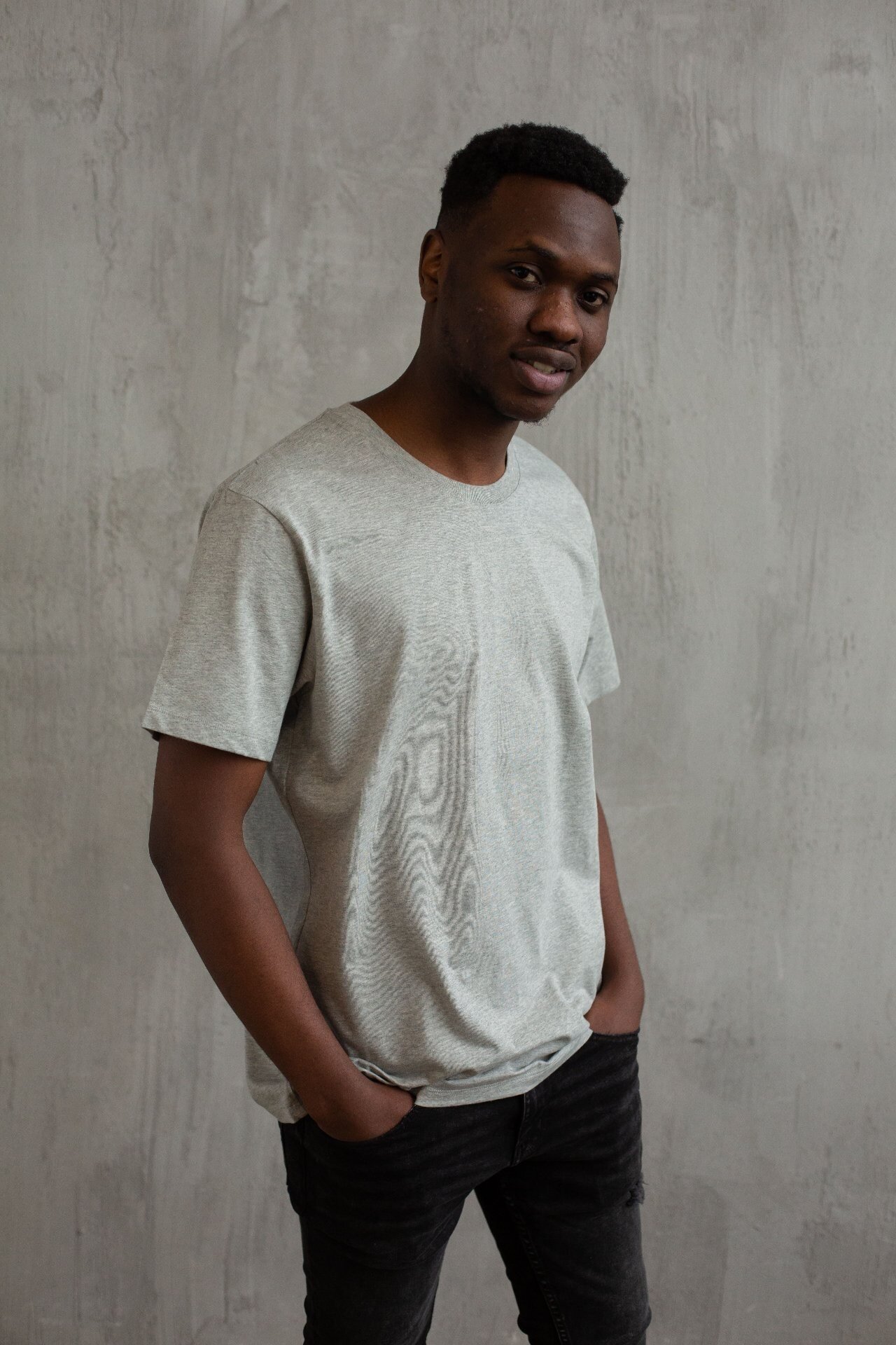 Men's heather grey crew-neck t-shirt styled against a concrete wall