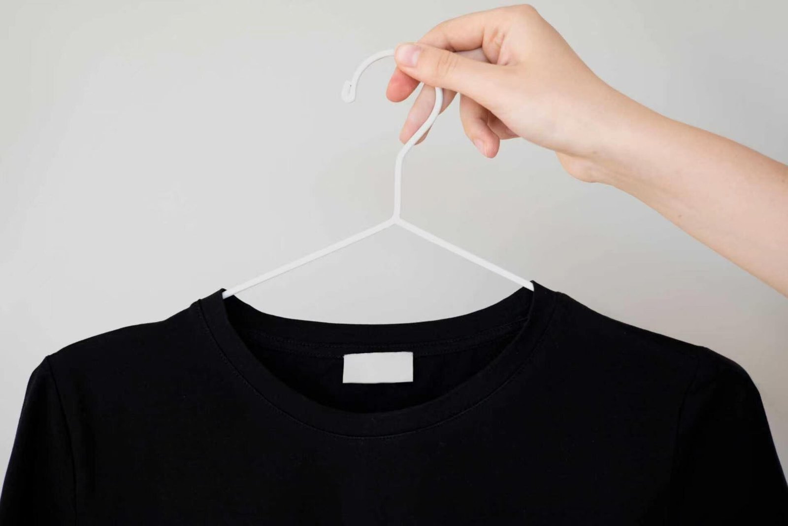 Black crew-neck t-shirt on a hanger with blank neck label, ready for custom labelling