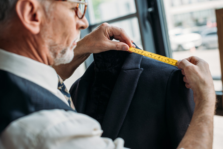 Quality control checking jacket measurements with a tape measure during private label production