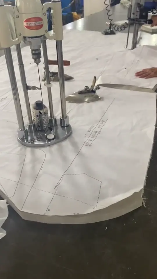 Straight-knife cutter and paper pattern on layered fabric