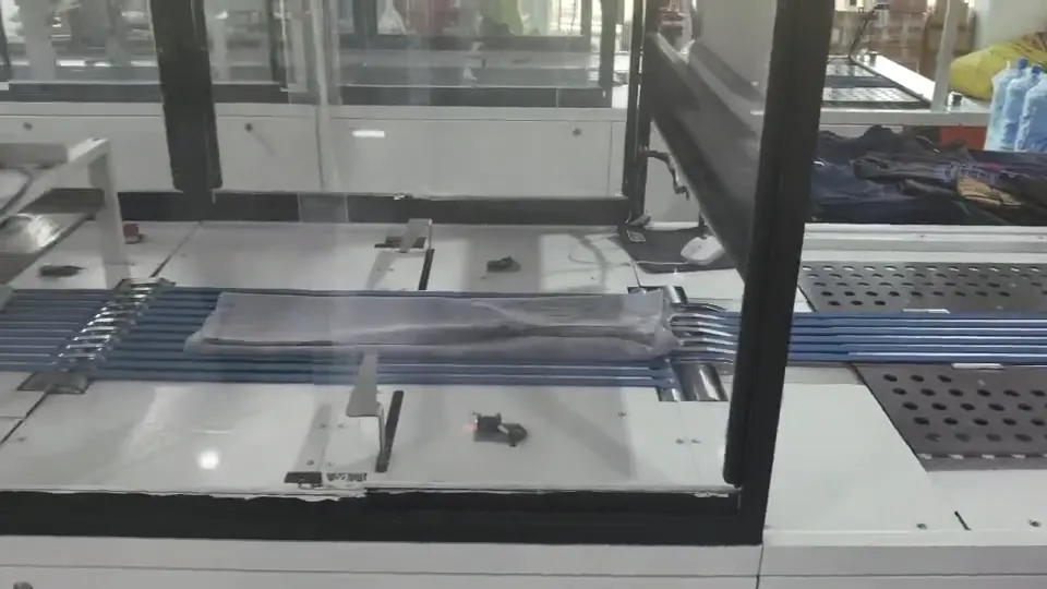 Folded garment moving through enclosed conveyor equipment